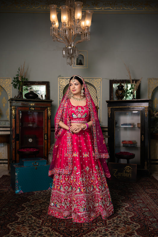 A stunning pink red raw silk bridal lehenga featuring zardozi birds motifs sequins and moti work lehenga beautifully adorned with fine craftsmanship and exquisite detailing, perfect for festive and special occasions.