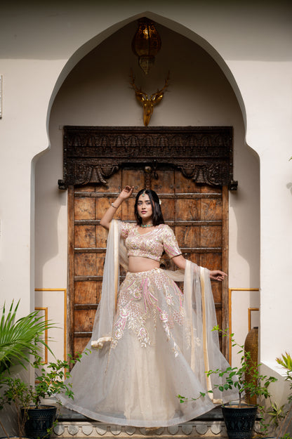 A stunning light grayish orange net lehenga featuring sequins work lehenga beautifully adorned with fine craftsmanship and exquisite detailing, perfect for festive and special occasions.