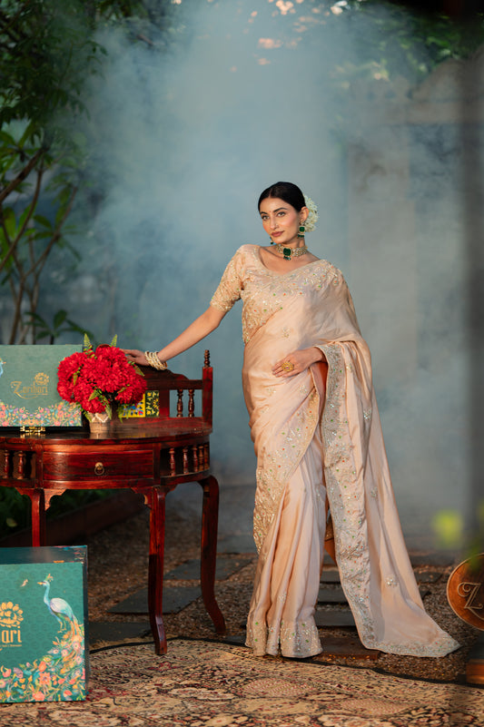 A stunning beige sand raw silk saree featuring aari zardozi gota patti work saree beautifully adorned with fine craftsmanship and exquisite detailing, perfect for festive and special occasions.